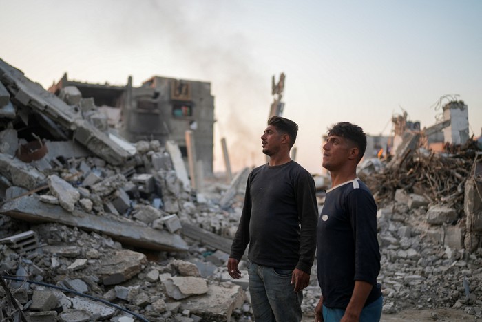 Palestinian twins Mahmoud and Ibrahim Al-Atout, who were separated during the war when Ibrahim was displaced to the southern part of Gaza at Israels order, carry a table as they search for belongings through the rubble of their destroyed house after being reunited, in Jabalia, northern Gaza Strip, January 29, 2025. REUTERS/Osama Al-Arabid