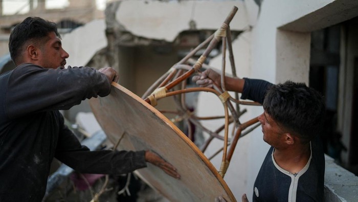 Dipisahkan Perang, Saudara Kembar Ini Bertemu di Rumah Mereka yang Hancur Palestinian twins Mahmoud and Ibrahim Al-Atout, who were separated during the war when Ibrahim was displaced to the southern part of Gaza at Israel's order, carry a table as they search for belongings through the rubble of their destroyed house after being reunited, in Jabalia, northern Gaza Strip, January 29, 2025. REUTERS/Osama Al-Arabid