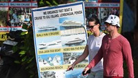 Dua orang wisatawan mancanegara berkeliling sambil menikmati keindahan Pantai Kuta. 