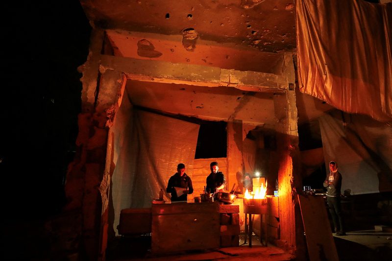 Palestinians warm themselves by a fire, during a power cut, amid a ceasefire between Israel and Hamas, in Gaza City, February 3, 2025. REUTERS/Dawoud Abu Alkas