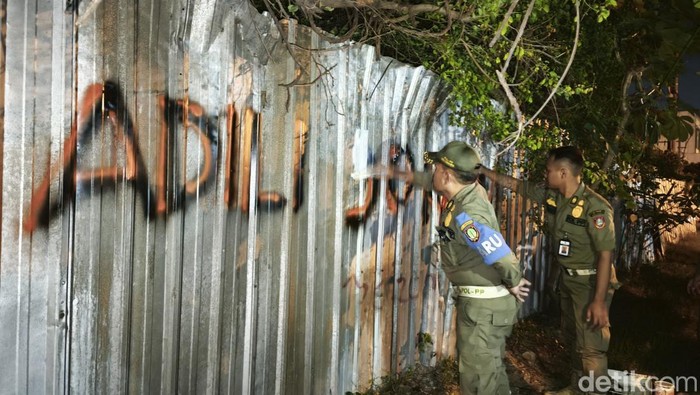Satpol PP Kota Solo saat menghapus vandalisme bertuliskan Adili Jokowi di Jalan Prof. Soeharso, Kecamatan Laweyan, Kota Solo, Selasa (4/2/2025).