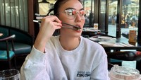 Sejak menetap di Amerika Serikat, tampilannya yang keren menyesuaikan sekitarnya. Makan di restoran saja ia mengenakan atasan abu-abu dengan kacamata elegan. Foto: Instagram/agnezmo