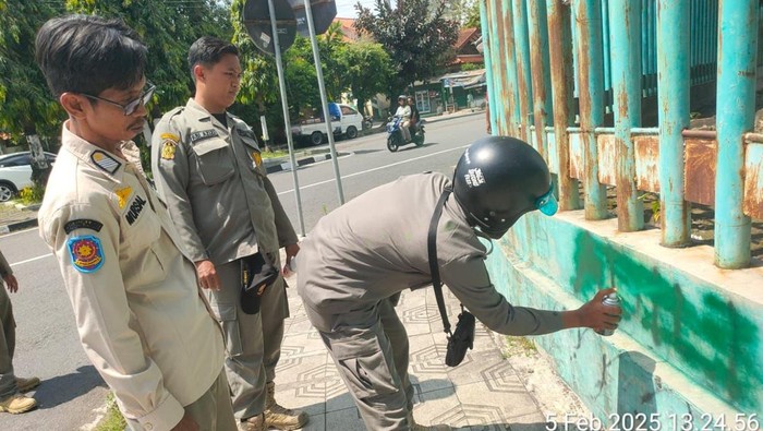 Satpol PP Kota Jogja saat membersihkan aksi vandalisme bertuliskan Adili Jokowi di Stadion Mandala Krida, Rabu (5/2/2025).