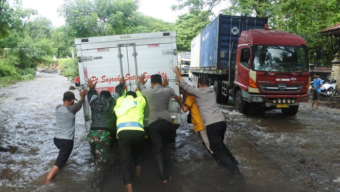 Personel polisi, TNI dan warga mendorong kendaraan yang mogok akibat menerobos banjir di jalan raya pantai utara (Pantura) Desa Pasir Putih, Bungatan, Situbondo, Jawa Timur, Rabu (5/2/2025). Banjir luapan air sungai tersebut membawa material batu dan pasir yang menutupi jalan raya Pantura Situbondo sehingga mengakibatkan kemacetan sekitar delapan kilometer dari arah Surabaya ke Banyuwangi dan sebaliknya. ANTARA FOTO/Seno/nym.