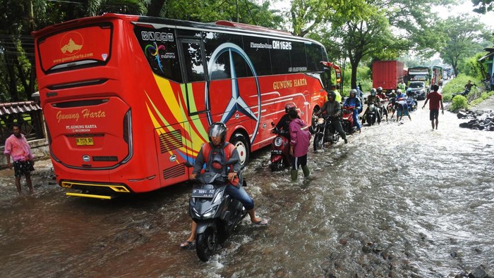 Personel polisi, TNI dan warga mendorong kendaraan yang mogok akibat menerobos banjir di jalan raya pantai utara (Pantura) Desa Pasir Putih, Bungatan, Situbondo, Jawa Timur, Rabu (5/2/2025). Banjir luapan air sungai tersebut membawa material batu dan pasir yang menutupi jalan raya Pantura Situbondo sehingga mengakibatkan kemacetan sekitar delapan kilometer dari arah Surabaya ke Banyuwangi dan sebaliknya. ANTARA FOTO/Seno/nym.