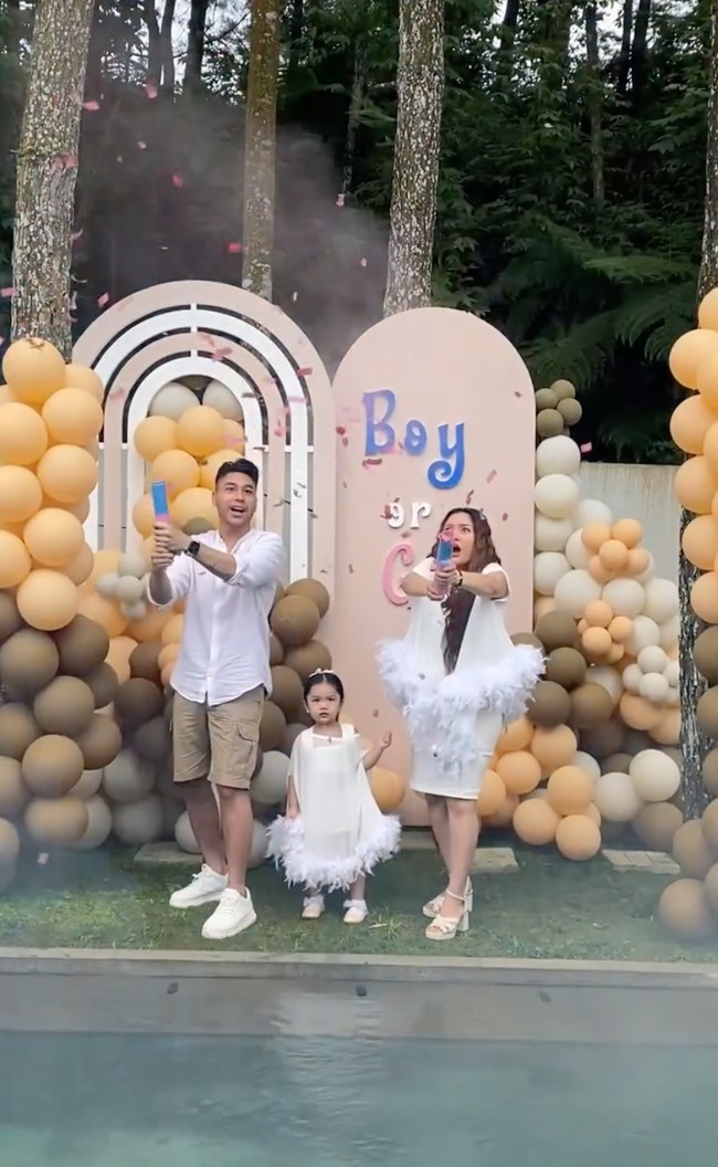 Masuk ke inti acara, Krisjiana dan Siti tampak membuka confefetti yang dipegangnya. Confetti tersebut berisi warna yang melambangkan jenis kelamin sang jabang bayi. Terlihat confetti tersebut mengeluarkan potongan kertas berwarna pink yang menandakan calon anak kedua Siti dan Krisjiana berjenis kelamin perempuan. Foto: Instagram/@sitibadriahh