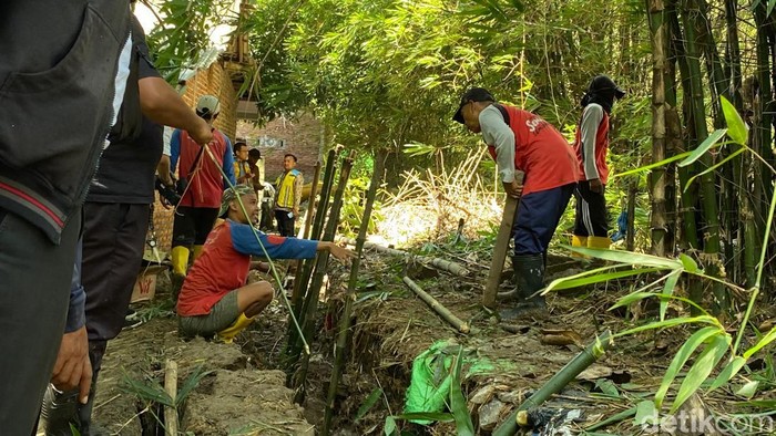 Warga memperbaiki talut yang jebol.