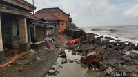 Potret ambruknya tembok pembatas pantai. Materialnya berserakan hingga menimpa rumah warga.