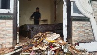 Warga membersihkan sampah-sampah yang masuk ke dalam rumah usai peristiwa gelombang besar.