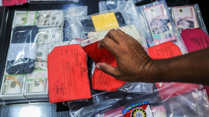 Pengungkapan Peredaran Uang Palsu di Banten Petugas kepolisian menata barang bukti uang palsu sebelum pengungkapan peredaran uang palsu di Mapolda Banten, Kota Serang, Banten, Rabu (6/2/2025). Polda Banten berhasil mengamankan sebanyak 14 tersangka pengedar sekaligus produksi uang palsu yang beraksi di wilayah Tangerang dengan barang bukti berupa mesin cetak, uang palsu sebanyak 2037 lembar dengan rincian pecahan Rp100.000 sebanyak 1600 lembar, pecahan Rp50.000 sebanyak 437 lembar, serta mata uang asing Real Brasil sebanyak 200 lembar, dan 1034 lembar mata uang dolar Amerika Serikat. ANTARA FOTO/Muhammad Bagus Khoirunas/foc.