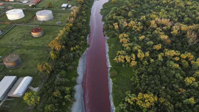 The Sarandi stream,  dyed red due to unknown contaminants allege residents, flows into the Río de la Plata on the outskirts of Buenos Aires, Argentina, Thursday, Feb. 6, 2025. (AP Photo/Rodrigo Abd)