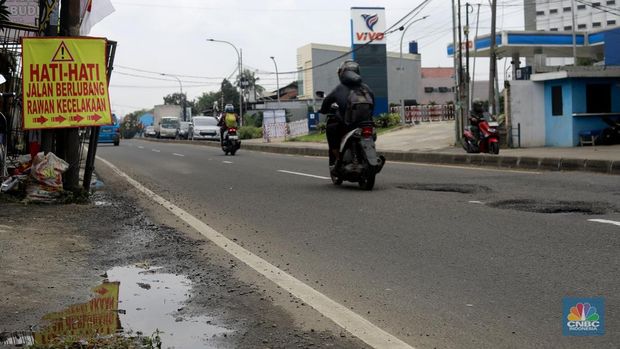 Pengendara melewati jalan rusak berlubang di Jalan Raya Parung-Ciputat, Bojongsari, Kota Depok, Jawa Barat, Jumat (7/1/2025). (CNBC Indonesia/Muhammad Sabki)