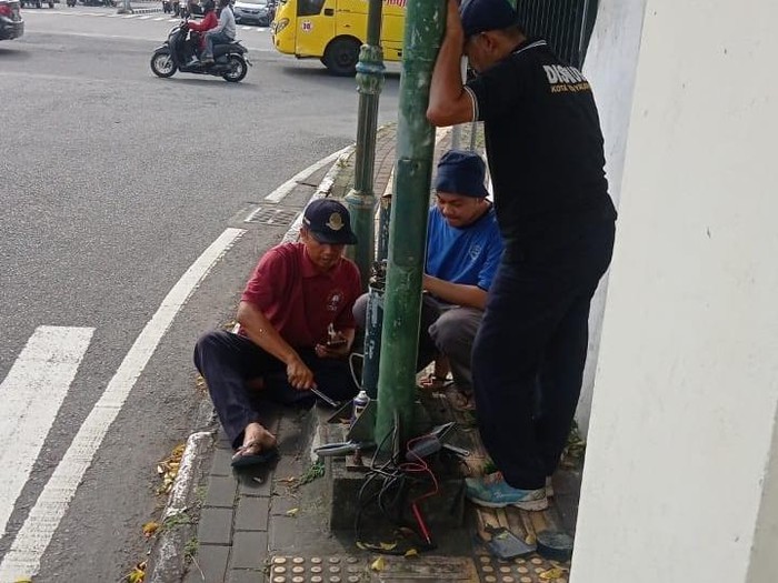 Petugas Dishub Kota Jogja sedang memperbaiki lampu APILL di simpang Jetis, Jogja, Jumat (7/2/2025).