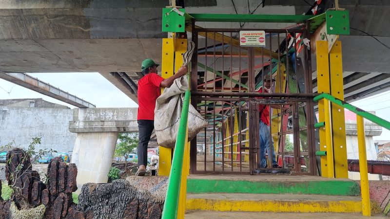 Warga memanjat dari sisi samping JPO kolong flyover Kalibata untuk melewati pagar yang menujupi akses mereka (Taufiq/detikcom)