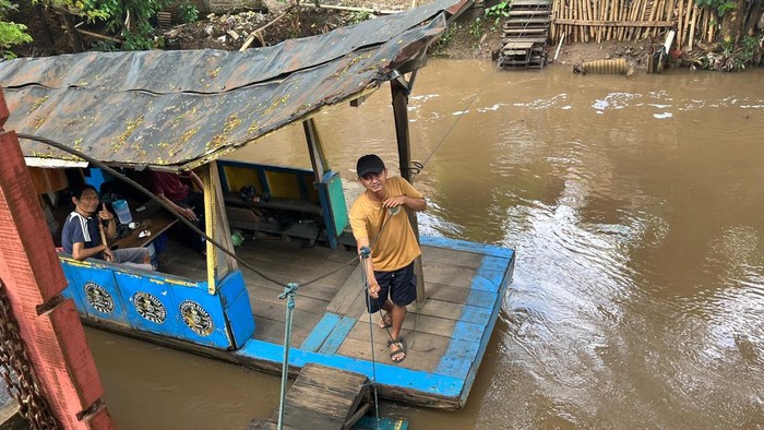 Hermawan saat menarik perahu eretnya