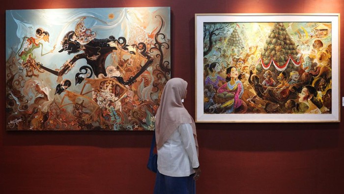 Pengunjung mengamati lukisan pada pameran lukisan bertema Dolan Wonosalam di Galeri Merah Putih, komplek Balai Pemuda, Surabaya, Jawa Timur, Sabtu (8/2/2025). Pameran lukisan karya Triyoso Yusuf itu merekam berbagai kegiatan seni dan budaya yang digelar di Wonosalam, Kabupaten Jombang dalam kanvas, di antaranya Jazz Kampoeng Djawi, Bancakan Salak Galengdowo, dan Kenduren Wonosalam.