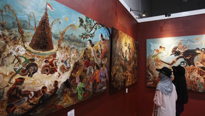 Pengunjung mengamati lukisan pada pameran lukisan bertema Dolan Wonosalam di Galeri Merah Putih, komplek Balai Pemuda, Surabaya, Jawa Timur, Sabtu (8/2/2025). Pameran lukisan karya Triyoso Yusuf itu merekam berbagai kegiatan seni dan budaya yang digelar di Wonosalam, Kabupaten Jombang dalam kanvas, di antaranya Jazz Kampoeng Djawi, Bancakan Salak Galengdowo, dan Kenduren Wonosalam.