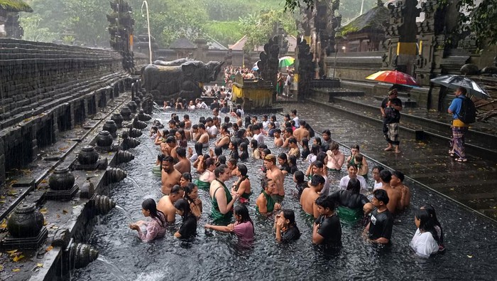 Umat Hindu berbaur dengan wisatawan mancanegara saat melakukan ritual melukat atau pembersihan diri pada hari Banyu Pinaruh di Pura Tirta Empul, Tampaksiring, Gianyar, Bali, Minggu (9/2/2025). Umat Hindu di Bali tetap menjalani ritual yang digelar setiap enam bulan sekali yakni sehari setelah Hari Raya Saraswati tersebut meski hujan deras mengguyur kawasan itu. ANTARA FOTO/Nyoman Hendra Wibowo/foc.