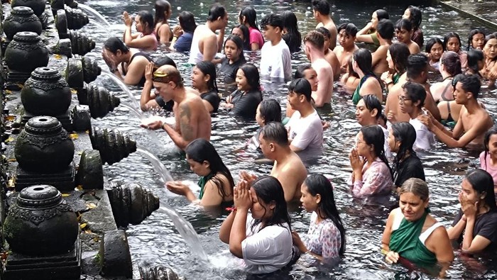 Umat Hindu berbaur dengan wisatawan mancanegara saat melakukan ritual melukat atau pembersihan diri pada hari Banyu Pinaruh di Pura Tirta Empul, Tampaksiring, Gianyar, Bali, Minggu (9/2/2025). Umat Hindu di Bali tetap menjalani ritual yang digelar setiap enam bulan sekali yakni sehari setelah Hari Raya Saraswati tersebut meski hujan deras mengguyur kawasan itu. ANTARA FOTO/Nyoman Hendra Wibowo/foc.