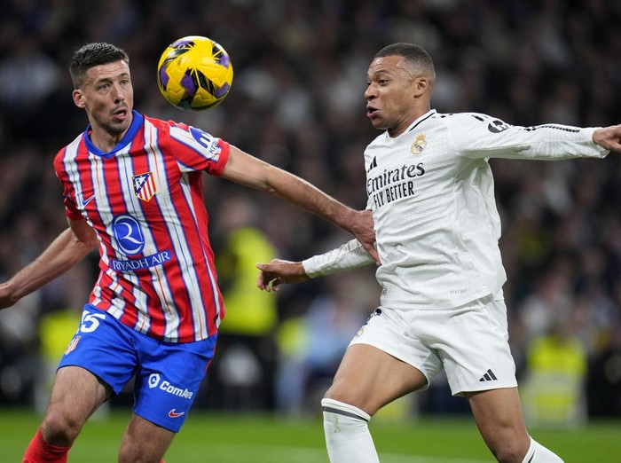 Atletico Madrid's Clement Lenglet vies for the ball with Real Madrid's Kylian Mbappe, right, during a Spanish La Liga soccer match between Real Madrid and Atletico Madrid at the Santiago Bernabeu stadium in Madrid, Saturday, Feb. 8, 2025. (AP Photo/Manu Fernandez)