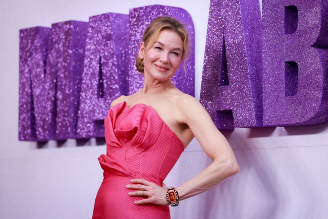 Renee tampil elegan dalam balutan gaun coral pink dengan potongan strapless, detail kerut pada bagian leher, serta bodice yang terstruktur. (Foto: Hanna Lassen/Getty Images)