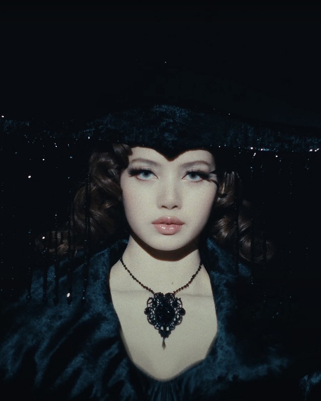 Ada pula gaya Lisa BLACKPINK memakai coat berwarna hitam dari ASHI Studio Fall Winter 24/25 Collection. Topi yang dikenakannya seolah menjadi statement. Item tersebut dirancang khusus oleh Sarah Mokol Millinery untuk Lisa beraksen rumbai. Foto: dok. YouTube LLOUD