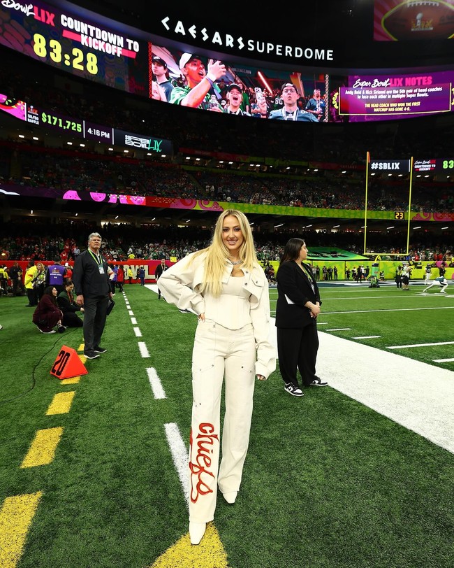 Dalam foto yang diunggah di Instagram, Brittany mengenakan busana serba putih dengan jaket crop dan celana jeans bertuliskan ‘chiefs’ saat hadir di lapangan Caesars Superdome, New Orleans, AS. Foto: Instagram Brittany Mahomes