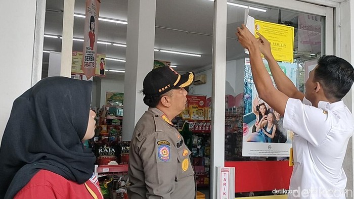 Petugas gabungan Bojonegoro memasang stiker tanda minimarket sudah berizin untuk membedakannya dengan yang bodong.