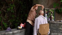 Pelanggan potong rambut di bawah pohon ini didominasi oleh orang tua. 