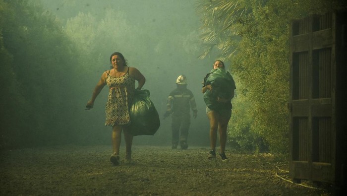 People carry their belongings following the spread of wildfires near Lautaro, Chile February 9, 2025 REUTERS/Hector Andrade     TPX IMAGES OF THE DAY
