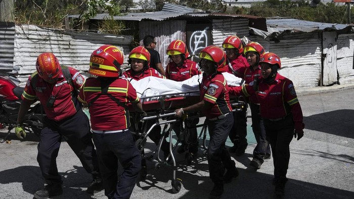 A soldier helps transport the body of a passenger who died in a bus crash on the outskirts of Guatemala City, Monday, Feb. 10, 2025. (AP Photo/Moises Castillo)