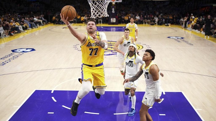 Los Angeles Lakers guard Luka Doncic (77) shoots as Utah Jazz guard Jordan Clarkson (00) and guard Johnny Juzang defend during the first half of an NBA basketball game, Monday, Feb. 10, 2025, in Los Angeles. (AP Photo/Mark J. Terrill)