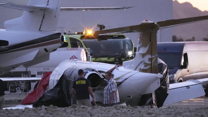 Penampakan 2 Pesawat yang Tabrakan di Bandara AS Firefighters work around the site of a crashed Learjet at Scottsdale Airport after it collided with a parked plane Monday, Feb. 10, 2025, in Scottsdale, Ariz. (AP Photo/Ross D. Franklin)