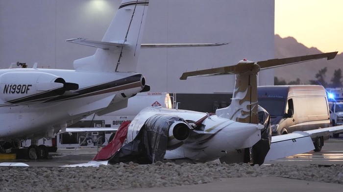 Firefighters work around the site of a crashed Learjet at Scottsdale Airport after it collided with a parked plane Monday, Feb. 10, 2025, in Scottsdale, Ariz. (AP Photo/Ross D. Franklin)