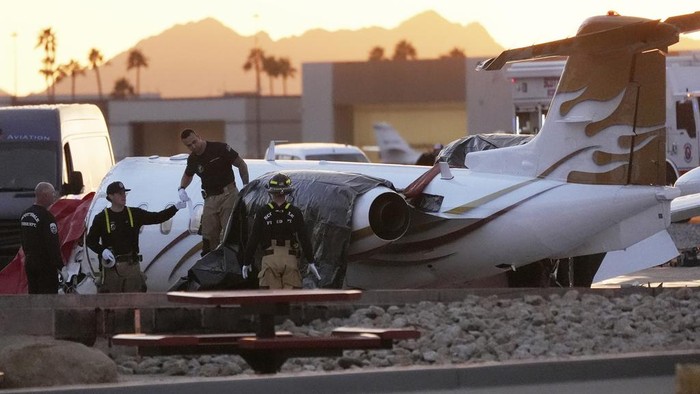 Penampakan 2 Pesawat yang Tabrakan di Bandara AS Firefighters work around the site of a crashed Learjet at Scottsdale Airport after it collided with a parked plane Monday, Feb. 10, 2025, in Scottsdale, Ariz. (AP Photo/Ross D. Franklin)
