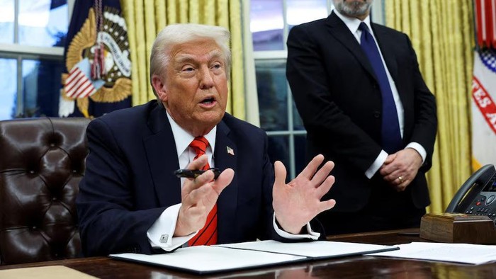 U.S. President Donald Trump speaks, as he signs executive orders, while Howard Lutnick stands in the background, in the Oval Office of the White House in Washington, U.S., February 10, 2025. REUTERS/Kevin Lamarque Purchase Licensing Rights