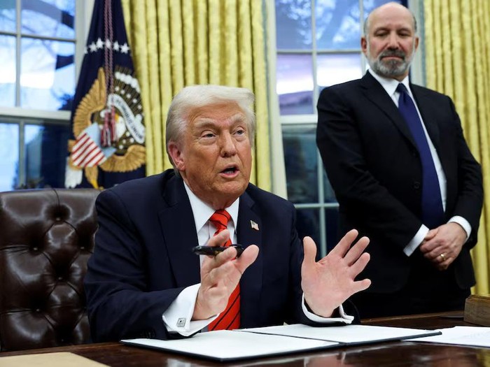 U.S. President Donald Trump speaks, as he signs executive orders, while Howard Lutnick stands in the background, in the Oval Office of the White House in Washington, U.S., February 10, 2025. REUTERS/Kevin Lamarque Purchase Licensing Rights