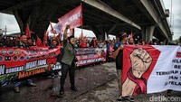 Para sopir truk berorasi sambil mengibarkan bendera organisasi dan membentangkan spanduk.  