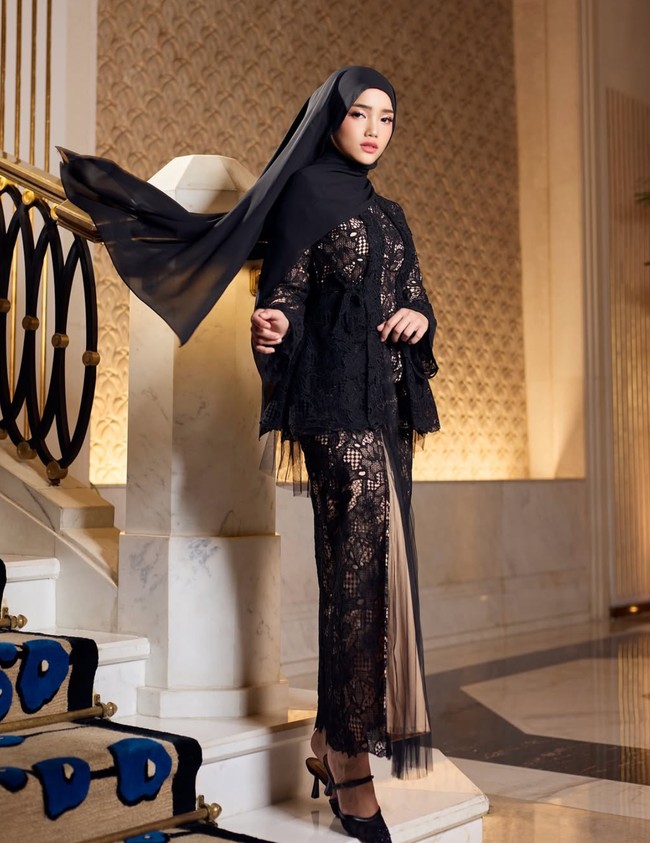 Kali ini wanita 22 tahun itu memodelkan busana llace hitam dipadukan dengan rok plisket berwarna coklat. Penampilannya semakin lengkap dengan hijab yang juga berwarna hitam. Foto: Instagram/@hijabista.hub