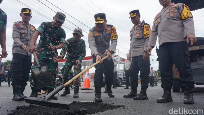Kapolres Jombang AKBP Ardi Kurniawan terjun langsung menambal jalan nasional yang berlubang.