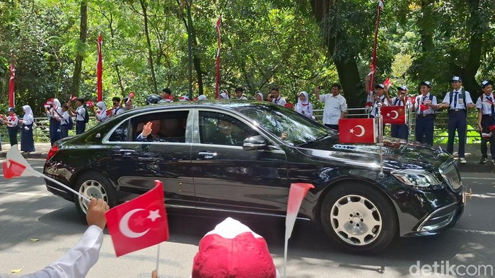 Kedatangan Presiden Turki Recep Tayyip Erdogan ke Istana Bogor disambut pelajar dan warga. Erdogan merespons dengan melambaikan tangan melalui jendela mobilnya. (M Sholihin/detikcom)