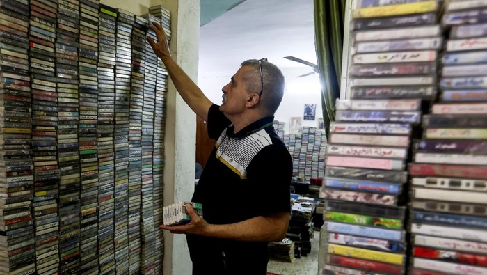 Sabah Al-Sudani who runs two shops selling audio cassettes and other vintage items of yesteryear, speaks with a customer at his shop, in Baghdad, Iraq, January 21, 2025. The once ubiquitous audio cassette is now seen by many as a relic of simpler times, but for Sudani the cassettes offer a nostalgia to a period he feels Arab music saw its peak. REUTERS/Ahmed Saad