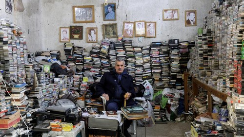 Sabah Al-Sudani who runs two shops selling audio cassettes and other vintage items of yesteryear, speaks with a customer at his shop, in Baghdad, Iraq, January 21, 2025. The once ubiquitous audio cassette is now seen by many as a relic of simpler times, but for Sudani the cassettes offer a nostalgia to a period he feels Arab music saw its peak. REUTERS/Ahmed Saad