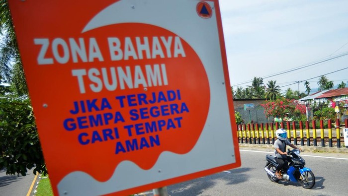 Pengendara sepeda motor melintas di dekat rambu zona bahaya tsunami yang baru dipasang di Jl Adinegoro Padang, Sumatera Barat, Selasa (11/2/2025). BPBD Padang menambah rambu-rabu zona bahaya (merah) gelombang tsunami di pesisir pantai kota itu yang dihuni sekitar 60 persen warga Padang. ANTARA FOTO/Iggoy el Fitra/rwa.