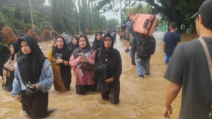Warga berjalan kaki melewati jalan poros Maros-Makassar terendam banjir.