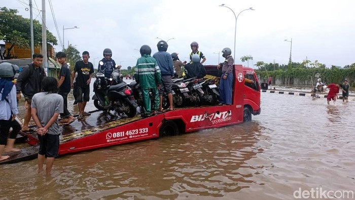Warga membuka jasa mengangkut motor untuk menyeberangi banjir di Jalan Perintis Kemerdekaan Makassar mengunakan mobil towing.
