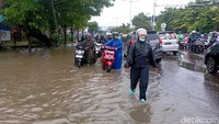 Foto: Warga mendorong motor yang mogok di Jalan Perintis Kemerdekaan Makassar. Kendaraan mogok karena nekat menerobos banjir.