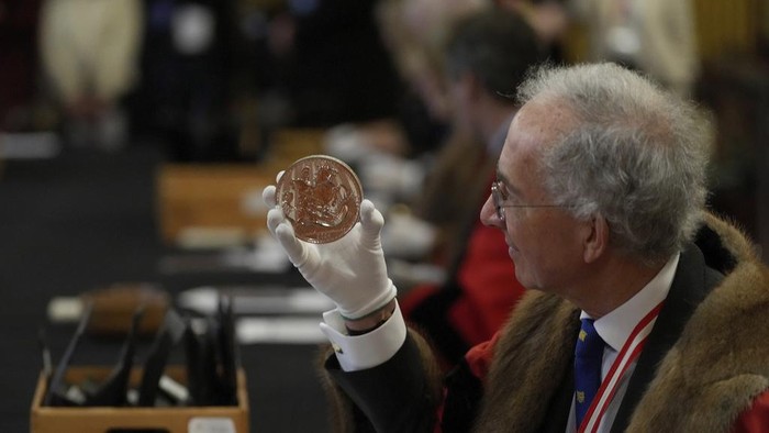 A warden looks through a magnifyer to check a 500 Pound coin during the 