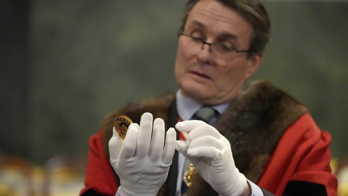 Begini Cara Inggris Memastikan Kualitas Mata Uang yang Diedarkan A warden looks through a magnifyer to check a 500 Pound coin during the