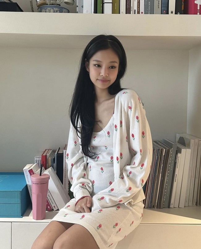 Coquette girl, Jennie BLACKPINK memancarkan kecantikannya memakai satu set gaun dan cardigan putih yang memiliki detail embroidery bunga berwarna merah. Penampilannya dilengkapi dengan bando, dan satu bagian rambutnya dibiarkan terurai. Foto: Instagram